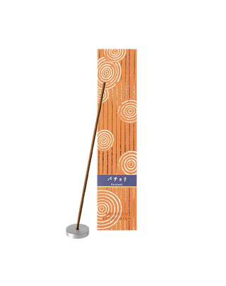 Patchouli incense sticks in a orange box with foiled Japanese Zen stone garden patterns, with one stick propped on an aluminum incense holder in front of the box.