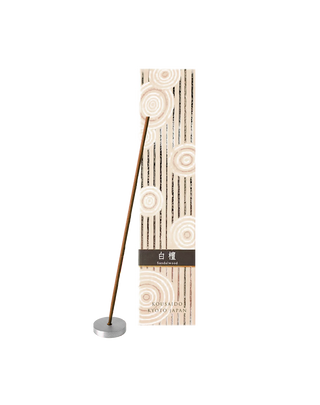 Sandalwood incense sticks in a beige and white box with foiled Japanese Zen stone garden patterns, with one stick propped on an aluminum incense holder in front of the box.