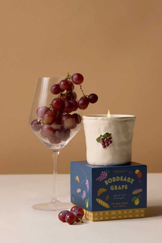 Paddywax Bordeaux Grape Bistro Collection ceramic candle with wine glass and fresh grapes, evoking a Parisian bistro ambience and luxurious fruity home fragrance gift idea.