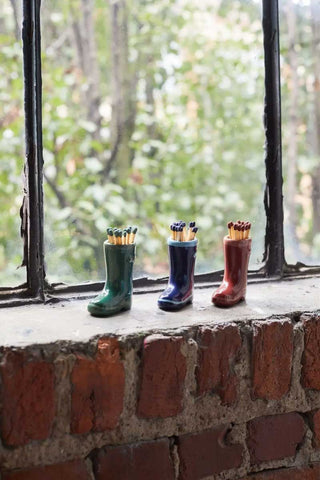 Paddywax ceramic Wellington boot match holders in green, navy, and red displayed on rustic windowsill, cozy countryside home décor scene with soft natural light and vintage charm.
