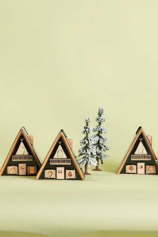 Paddywax Nordic Cabin ceramic A-frame incense house with tea light glowing and Palo-Santo smoke drifting, styled with rustic greenery for winter cabin décor and Christmas gift inspiration.