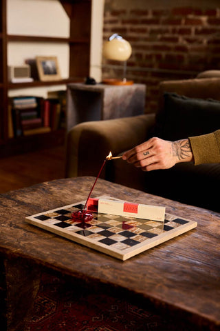 p.f. candle co hi fi collection plush vetiver person lighting incense stick on a chess board in a brick wall home with walnut bookshelf earthy musky home fragrance 