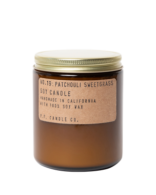 pf candle co patchouli sweetgrass soy candle in amber glass jar with kraft paper label and gold lid 50 hour burn time clean burn woody grassy smoky home fragrance inspired by relaxing afternoon in the garden